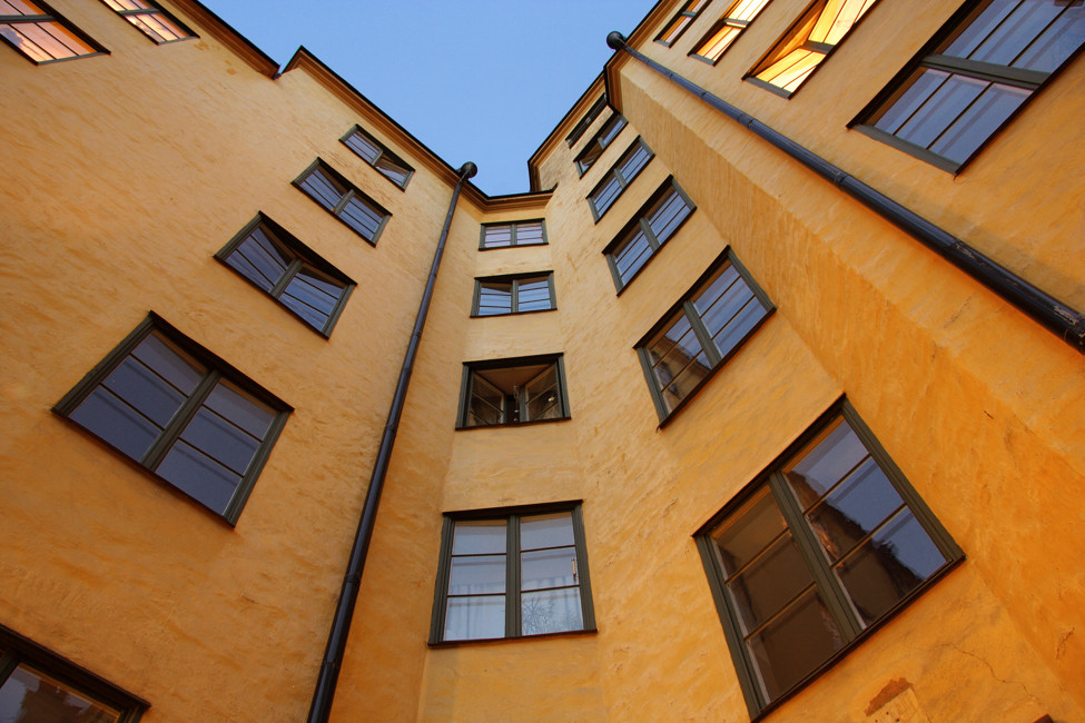 Bild på fasaden av ett gult lägenhetshus i grodperspektiv